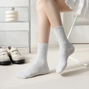 White mid-calf socks for women featuring cute embossed bows and lace ruffle trim details.
