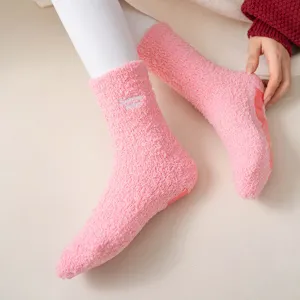 Pink fuzzy winter socks detail shot, cute embroidered letter design with cozy warmth inside.