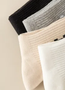 Close-up detail shot of ribbed knit socks showing soft texture and elastic cuff in multi colors.