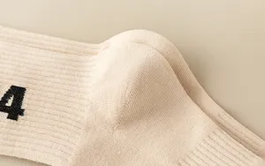 Beige ribbed knit sock detail close-up showing soft texture and distinctive side print design.