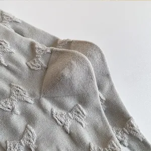 Close-up detail of grey cotton socks featuring all-over embossed bow jacquard pattern.