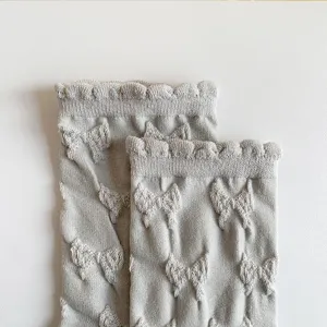 Detailed view of women's casual mid-calf socks featuring embossed bow patterns and sweet lace cuffs.