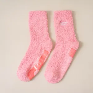 Pink fluffy fuzzy socks with non-slip grips and cute letter embroidery for cozy winter home wear.
