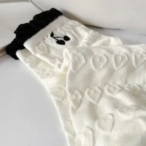 Calzini in maglia bianca da donna con polsini con volant neri, ricamo di ciliegie e cuori in rilievo.