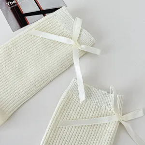 Close-up detail of white ribbed slouch socks featuring elegant satin bow for sweet girl style.