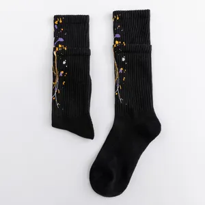 Detailed view of black paint splatter crew socks, featuring colorful printed accents inside.