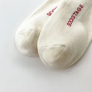 Primo piano dettagliato di calzini in cotone bianco con stampa a lettere rosse, trama pulita.