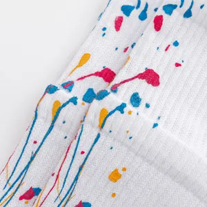 Detail shot of white athletic socks with colorful paint splatter design, soft fabric texture.