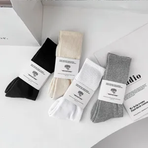 Classic ribbed cotton crew socks in four versatile colors featuring minimalist paper packaging bands.