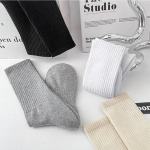 Detail shot of thick ribbed cotton crew socks in neutral solid colors displayed nicely on white.