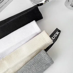 Detail shot of solid color men's cotton crew socks in black, white, beige, and grey.