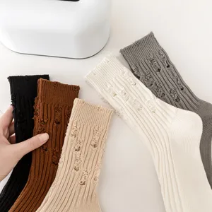 Close-up detail of distressed knit mid-tube cotton socks in assorted autumn colors