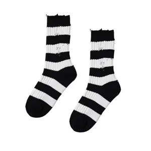 Close-up detail of black and white striped distressed socks with trendy grunge ripped design.