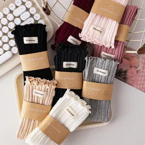 Close-up detail of cozy women's ruffled rib-knit crew socks with kraft paper bands in various colors.