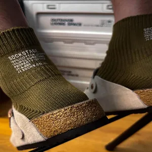 Close up view of olive green ribbed cotton ankle socks with white letter print detail.