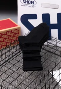 Detailed shot of black mid-tube cotton socks neatly stacked on a modern wire grid display.
