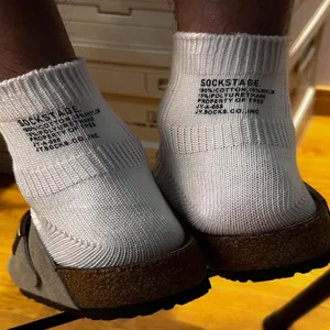 Close-up detail shot of white cotton short socks with rear letter print and ribbed knit design.