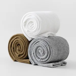 Detailansicht gerollter Baumwollsocken in Weiß, Braun und Grau mit grob gestrickter Struktur.
