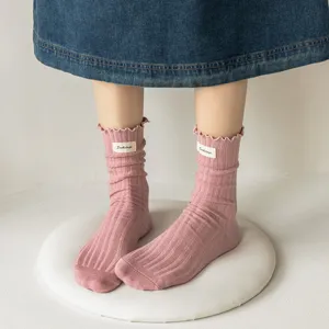 Pink ruffled mid-calf socks detail showcasing vertical striped knit texture and cute fabric label.