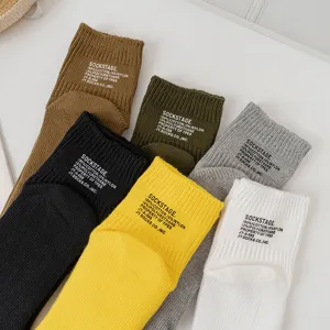 Close-up detail of thick knit solid color cotton socks with letter prints in multiple colors.