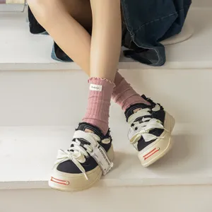 Detail shot of women pink ribbed cotton socks with sweet lettuce edge and knit label on stairs.