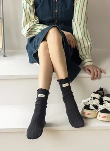 Black ribbed slouch socks featuring sweet lettuce edge and cute fabric label detail.