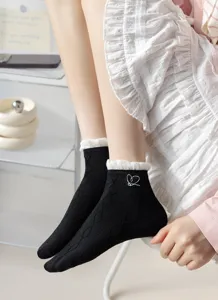Calzini corti da donna in cotone nero con polsini a volant bianchi e ricamo a cuoricino.