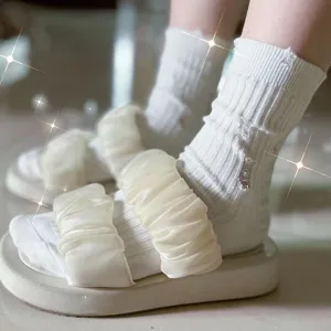 Detail shot of distressed white mid-tube socks paired with ruffled platform sandals, casual style.