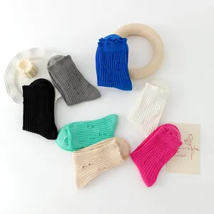 Close-up detail of multi-color distressed ribbed crew socks set styled with aesthetic props.