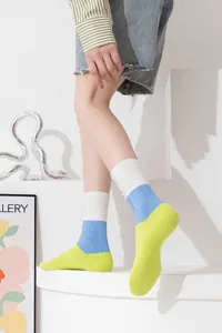 Close-up detail view of colorblock distressed mid-calf socks in a modern studio setting.