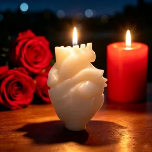 Détail d'une bougie parfumée en forme de cœur anatomique, lumière chaleureuse avec des roses rouges.