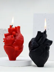 Vue détaillée de bougies parfumées en forme de cœur anatomique rouge et noir allumées.