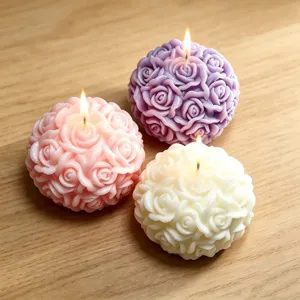 Nahaufnahme von drei kugelförmigen Rosen Duftkerzen in Rosa, Lila und Weiß brennend.
