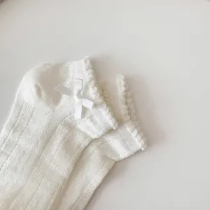 Close-up detail of women white cotton ankle socks featuring cute bow and delicate lace trim.