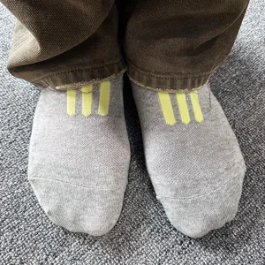 Detailed close-up view of grey short socks featuring stylish yellow three-stripe design.