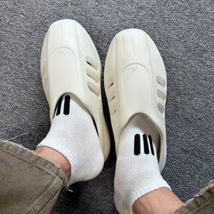 Detailed close-up view of casual foam slip-on shoes paired with white three-stripe ankle socks.