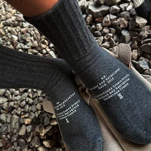 Dark grey ribbed cotton crew socks with white streetwear graphic text detail close up.