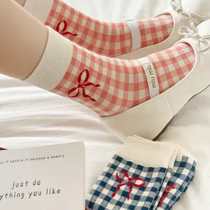 Cute pink gingham mid-calf socks with red bow and strap detail, stylish and comfortable.