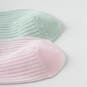Close-up detail of soft pastel ribbed socks in pink and green, showing delicate fabric texture.