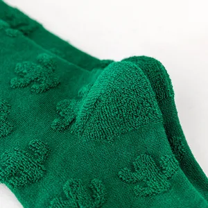 Nahaufnahme von grünen Frottee-Socken mit strukturierter Kaktus-Musterung im Detail.