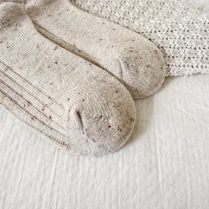 Detail view of thick flecked wool knit socks, soft texture and cozy winter design.