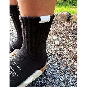 Men's black cotton mid-calf socks with white printed text and tag, casual streetwear style.