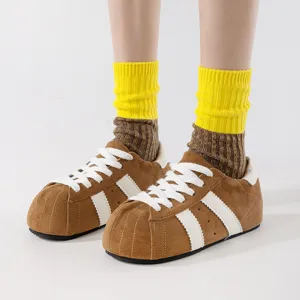 Cute brown plush bread shoes paired with stylish yellow and brown layered crew socks, detail shot.