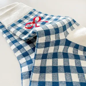 Blue and white checkered socks close up, sweet red bow detail, soft cotton fabric, cozy wear.