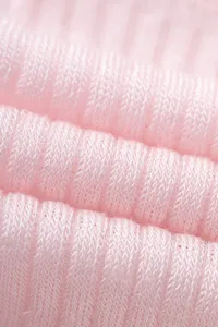 Detailed view of soft pink knitted fabric with vertical ribbed texture, breathable mesh surface.