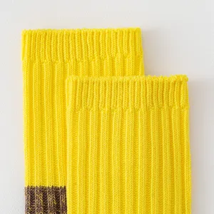 Yellow knitted mid-tube socks close-up showing thick rib texture and color block details.