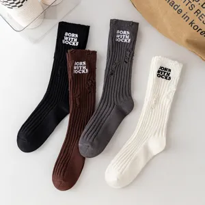 Detail view of winter distressed knitted crew socks with letter embroidery, available in multi colors.