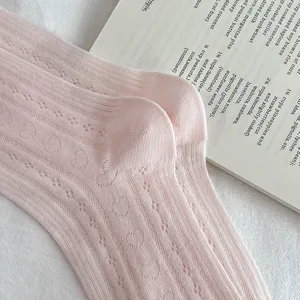 Nahaufnahme rosa Mesh-Stricksocken mit süßen Herzen und zarten Ballerina-Stil Details.
