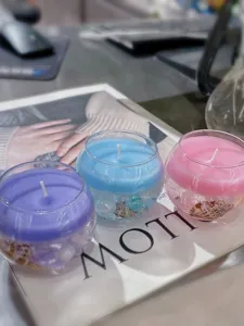 Detalle de cerca de velas perfumadas de colores en cuencos de vidrio con conchas.