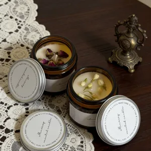 Detailed view of scented amber jar candles adorned with dried rose and jasmine flowers.